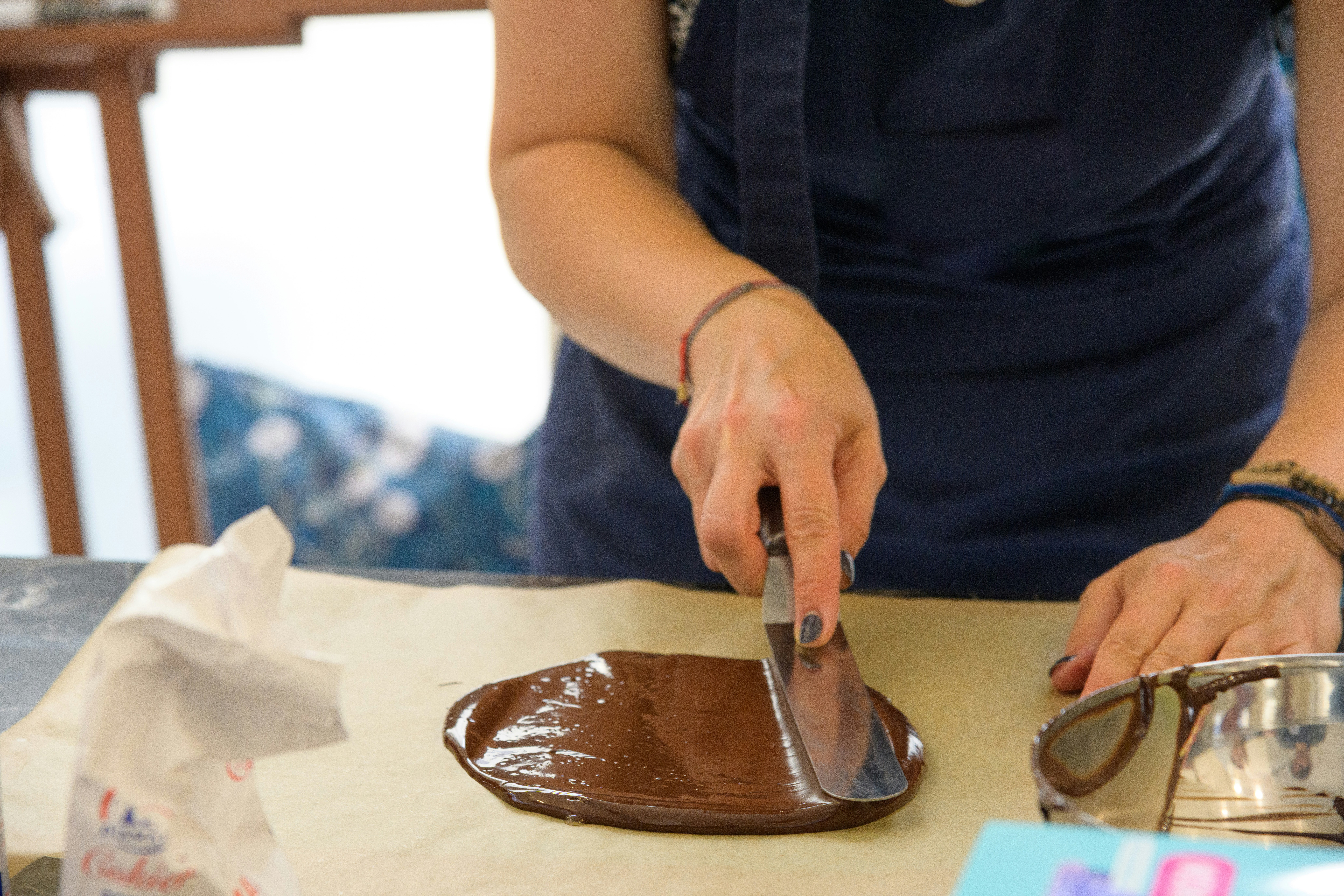 An artisan chocolatier tempering dark chocolate in a professional kitchen.